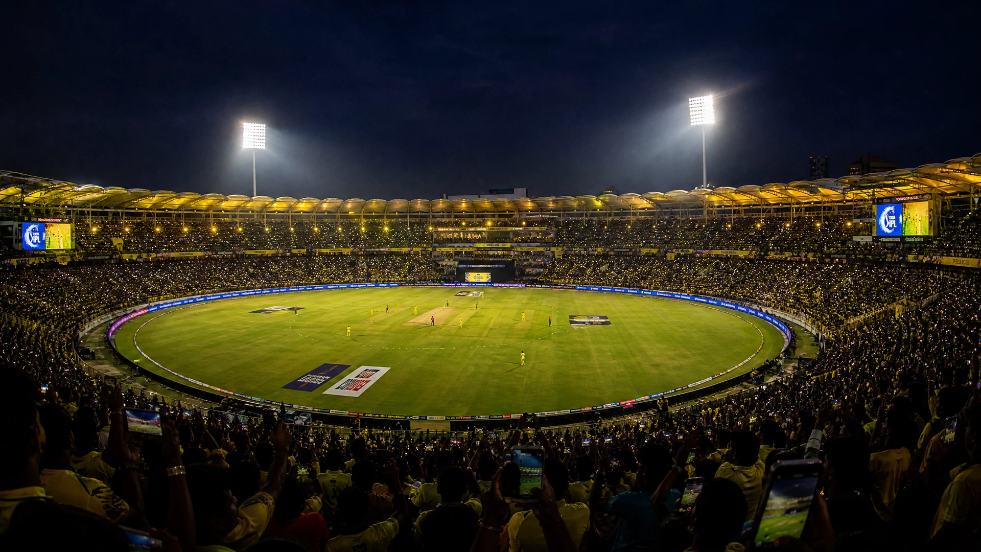 Cricket stadium at night during IPL match with floodlights